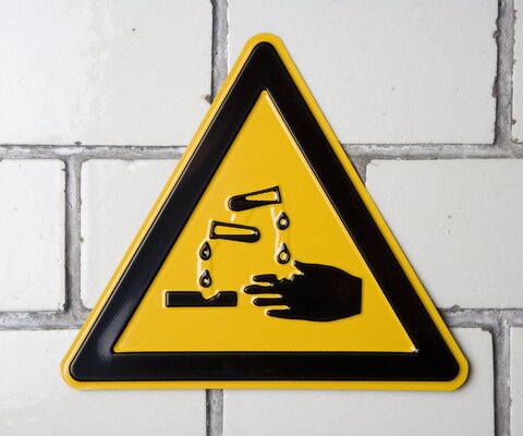 Gelbes Warnschild für Verätzungs- und Säuregefahr.
