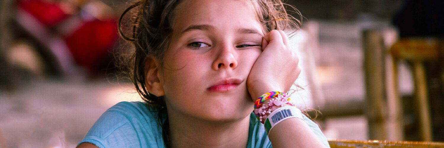  Ein Mädchen das müde und erschöpft ist und ihr Gesicht auf dem Arm abstützt.