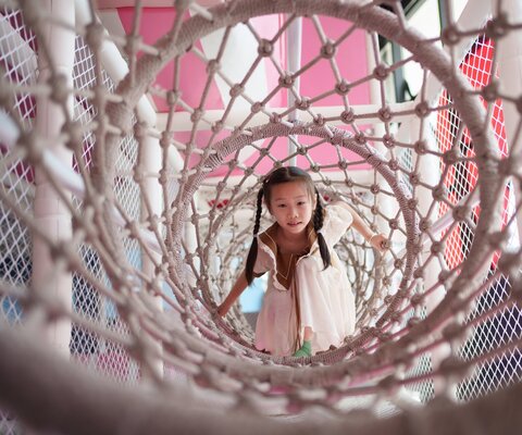 Kleines Mädchen spielt in einem Indoorspielplatz.