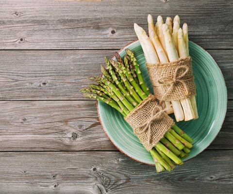  Weißer und grüner Spargel auf einem grünen Teller, aus Vogelperspektive fotografiert.