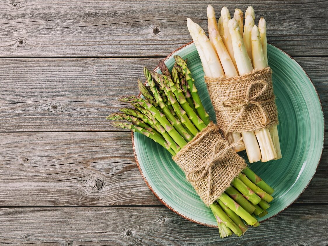  Weißer und grüner Spargel auf einem grünen Teller, aus Vogelperspektive fotografiert.