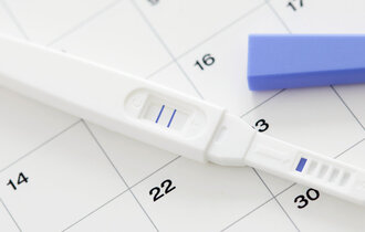 Pregnancy test showing positive result and calendar