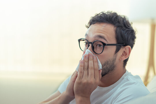 Ein Mann mit Brille putzt sich die Nase.