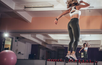 Eine Frau springt auf einem kleinen Trampolin in einem Fitnessstudio.