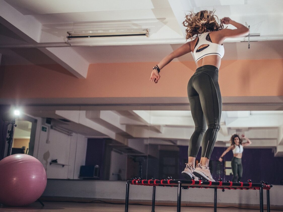 Eine Frau springt auf einem kleinen Trampolin in einem Fitnessstudio.