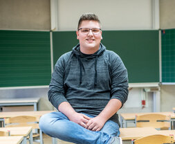 Das Foto zeigt Marek Fink, der in einem Klassenraum sitzt. 