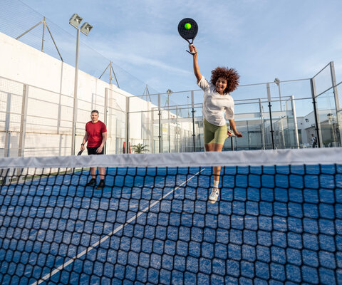 Zwei Personen sind auf einem Padelcourt und spielen Padel