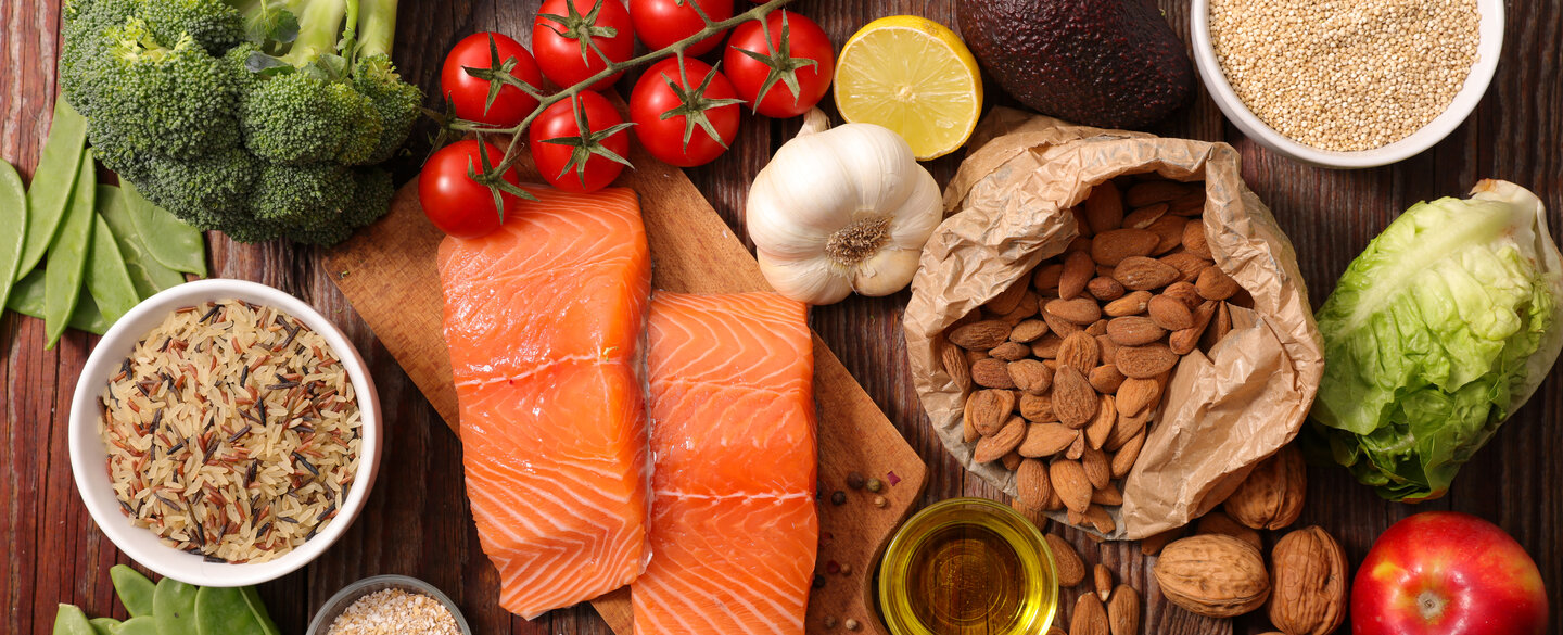 Lebensmittel, wie Lachs, Gemüse und Nüsse, liegen auf einem Brett.