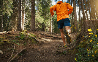 Ein Mann betreibt Trailrunning durch den Wald.