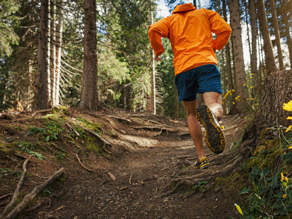 Ein Mann betreibt Trailrunning durch den Wald.