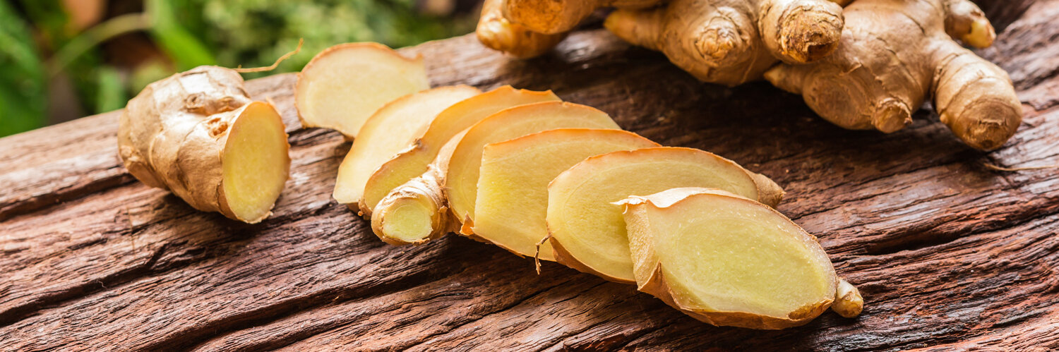 Eine geschnittene Ingwerknolle, daneben ganze Knollen.