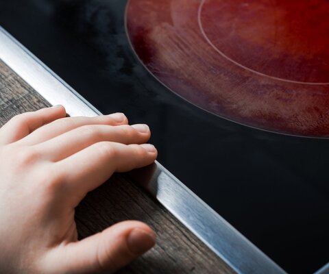 Das Foto zeigt eine rot-glühende Herdplatte. Kurz davor hat ein Kind seine Hand abgelegt.