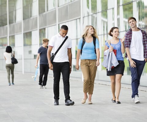 Eine Gruppe Studenten, welche über einen Campus laufen.