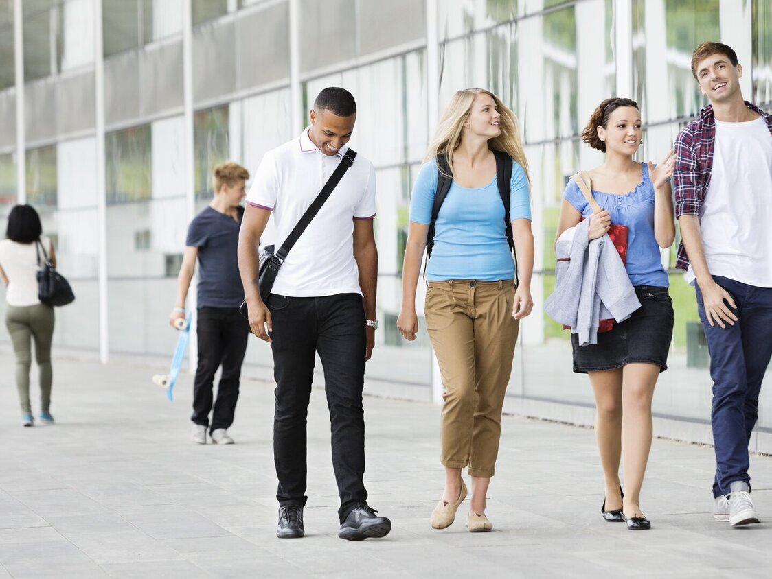 Eine Gruppe Studenten, welche über einen Campus laufen.
