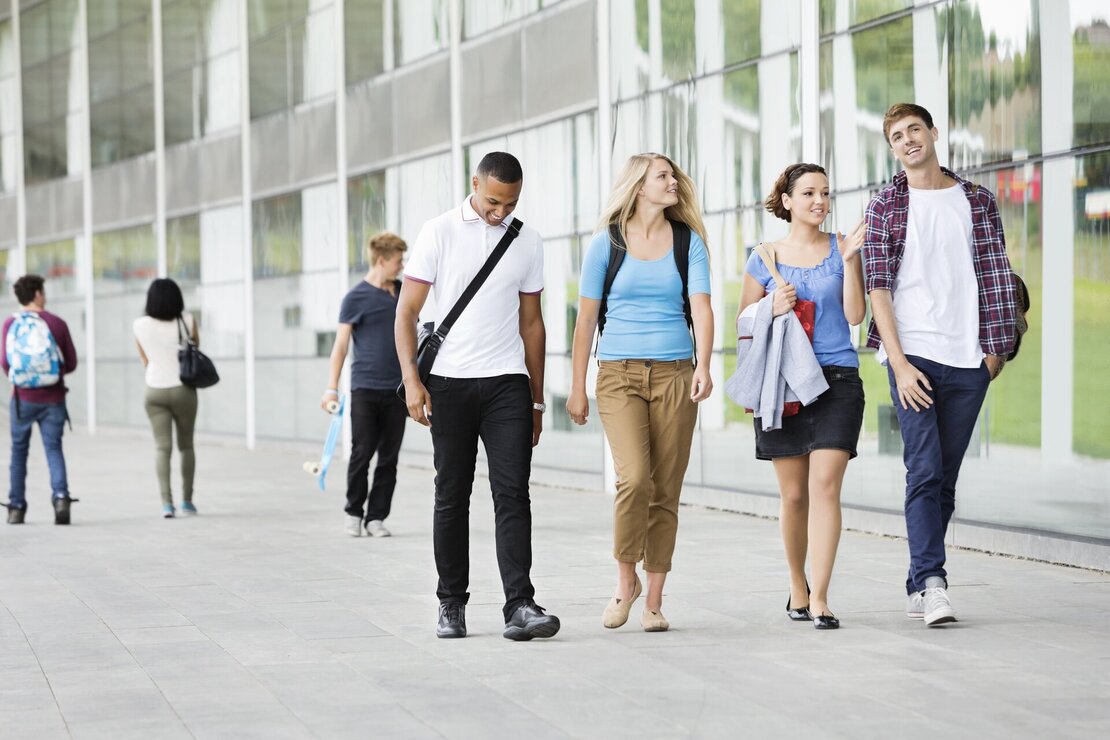 Eine Gruppe Studenten, welche über einen Campus laufen.