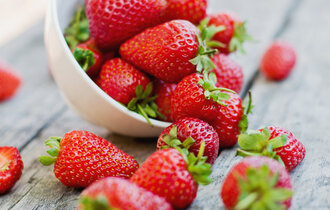 Eine Schale Erdbeeren, die umgekippt ist und einige Erdbeeren rausgefallen sind.