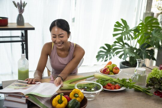 240410_artikelbild_frau-rezeptbuch-gemuese-kueche-kochen_gettyimages-1350952608.jpg Eine asiatische Frau steht an einem Tisch mit einem aufgeschlagenen Kochbuch und drum herum liegt Gemüse.