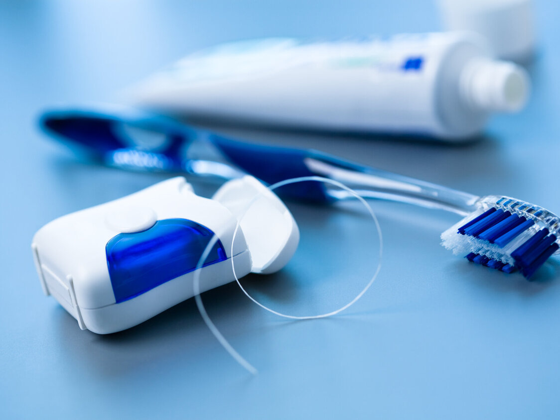 Eine Packung Zahnseide, eine Zahnbürste und eine Tube Zahnpasta 