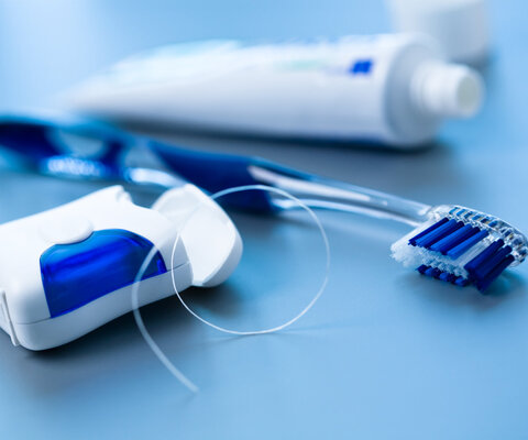 Eine Packung Zahnseide, eine Zahnbürste und eine Tube Zahnpasta 