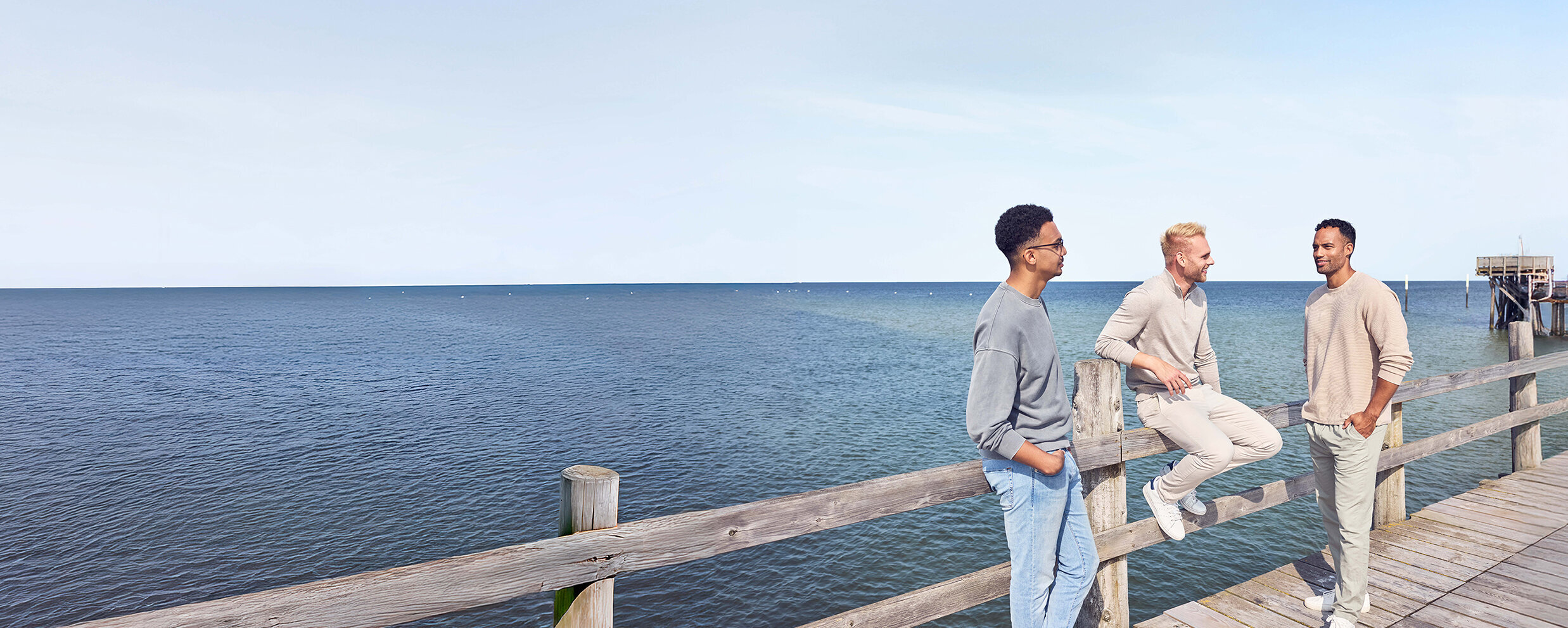 Drei Männer auf einem Steg am Meer.