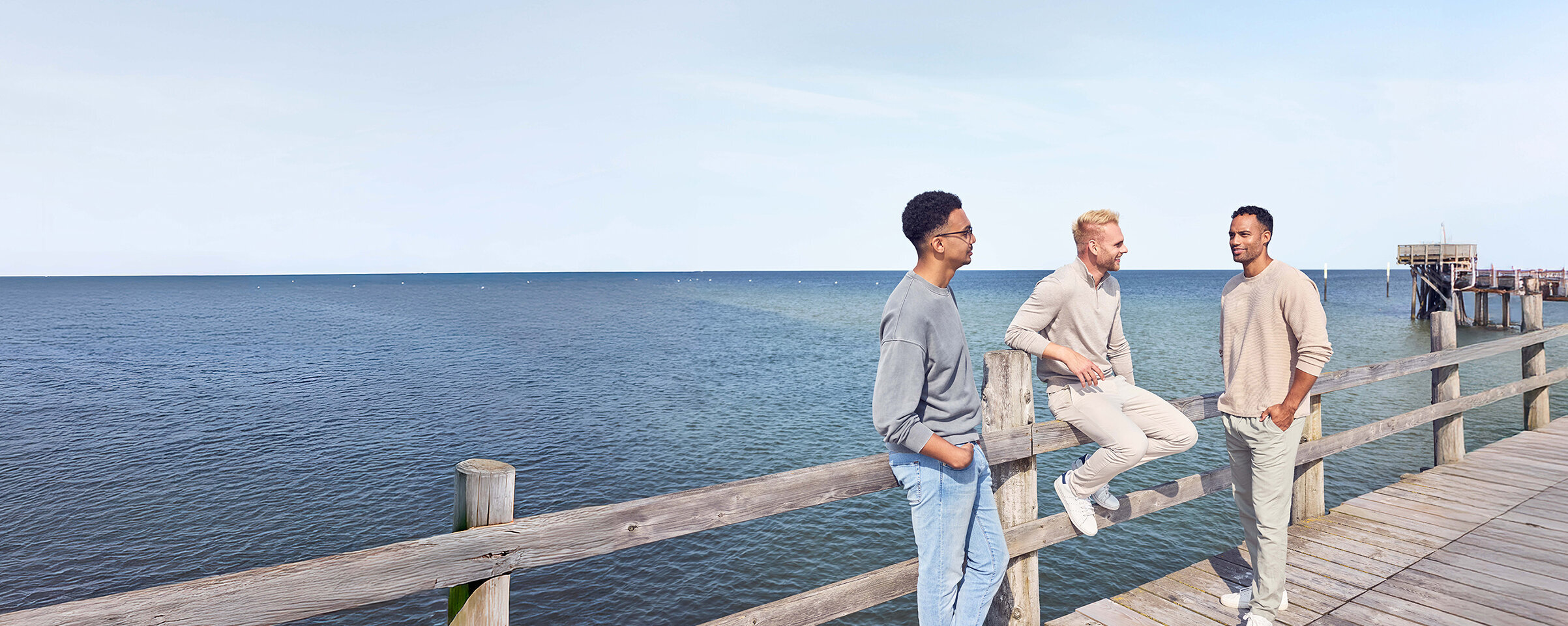 Drei Männer auf einem Steg am Meer.