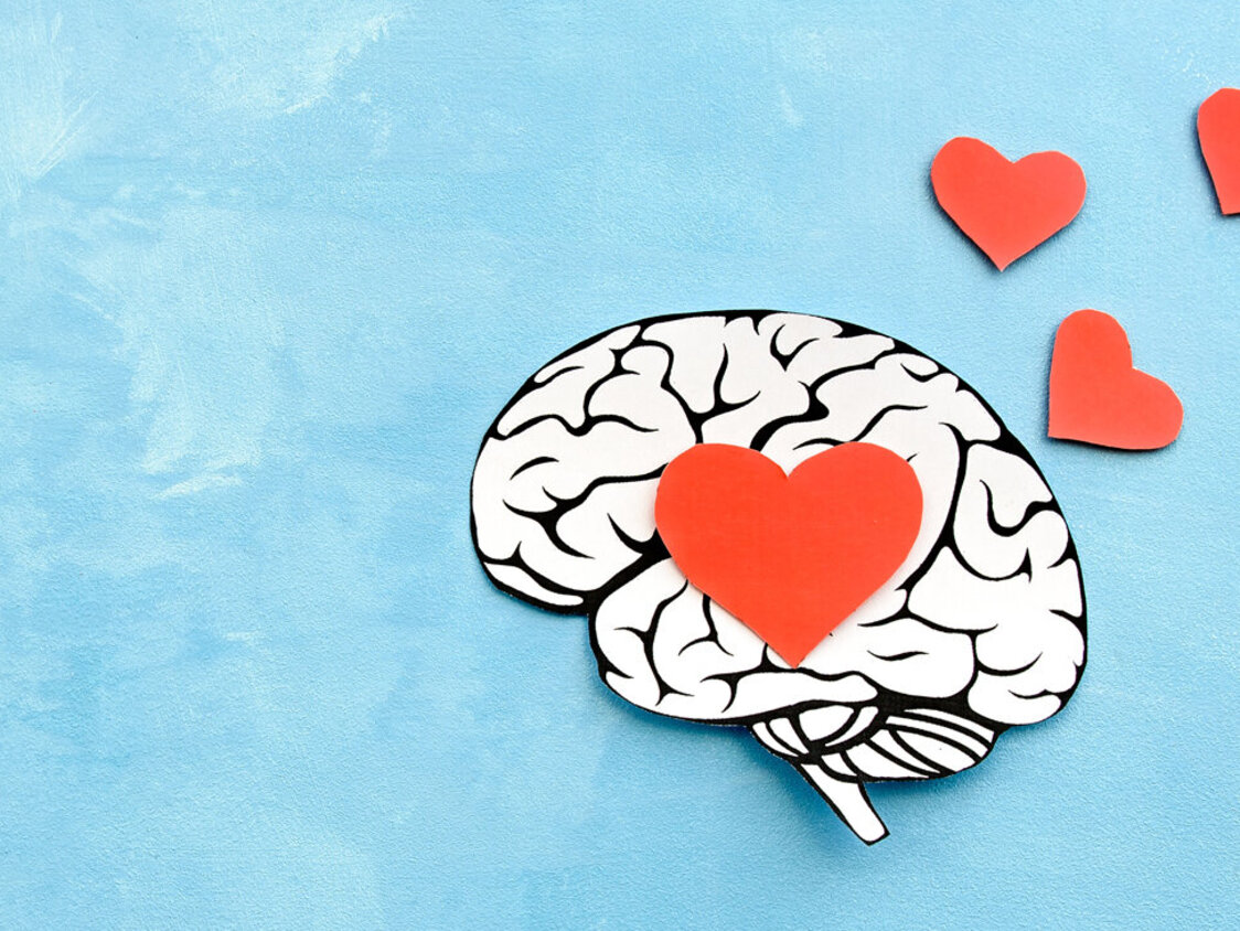 Ein Gehirn, gezeichnet auf einem blauen Untergrund mit roten Herzen.