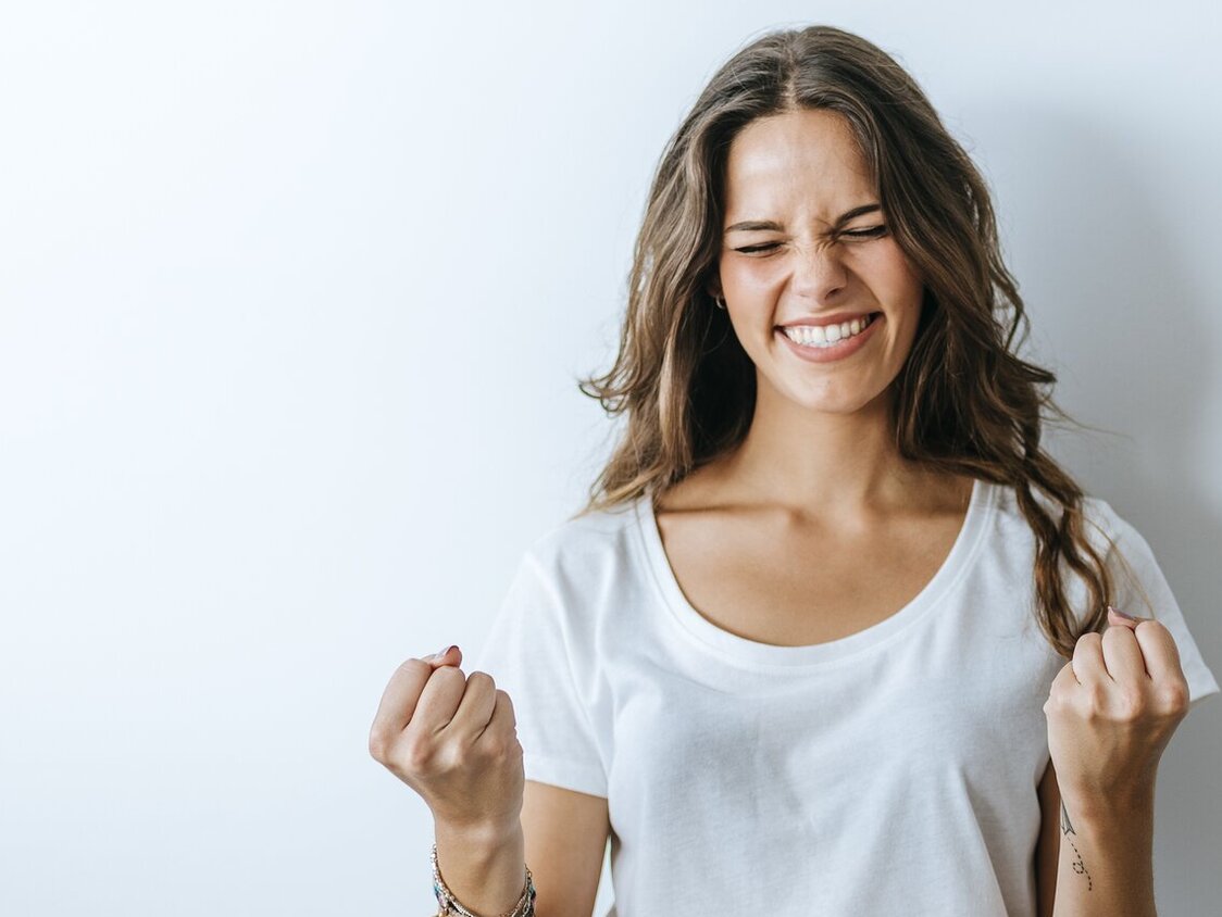Junge Frau ballt die Fäuste und jubelt.