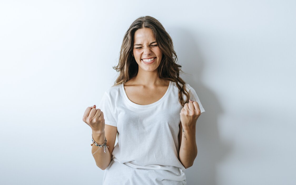 Junge Frau ballt die Fäuste und jubelt.