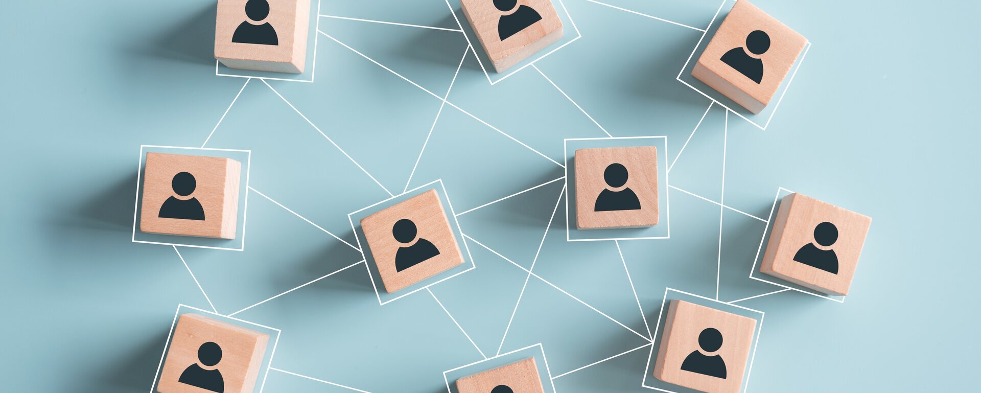 Kleine Holzwürfel mit aufgemalten Personen sind durch Linien verbunden.