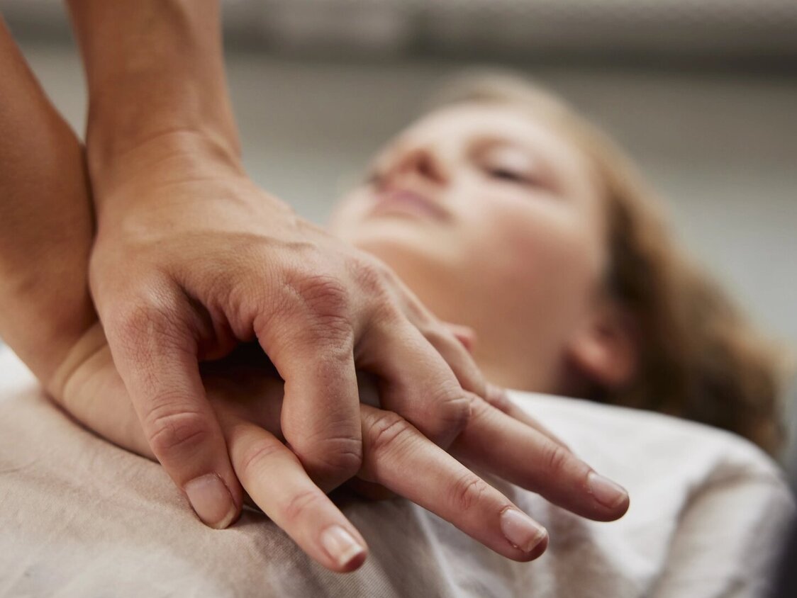 Frau liegt am Boden und wird wiederbelebt.