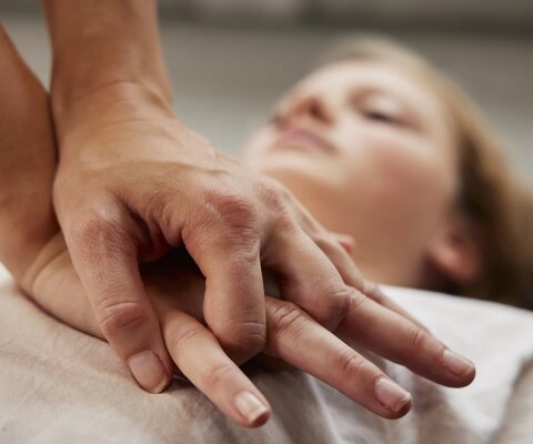 Frau liegt am Boden und wird wiederbelebt.
