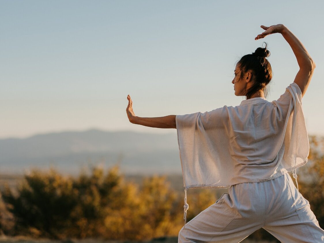 Eine Frau macht in der Natur Tai Chi.