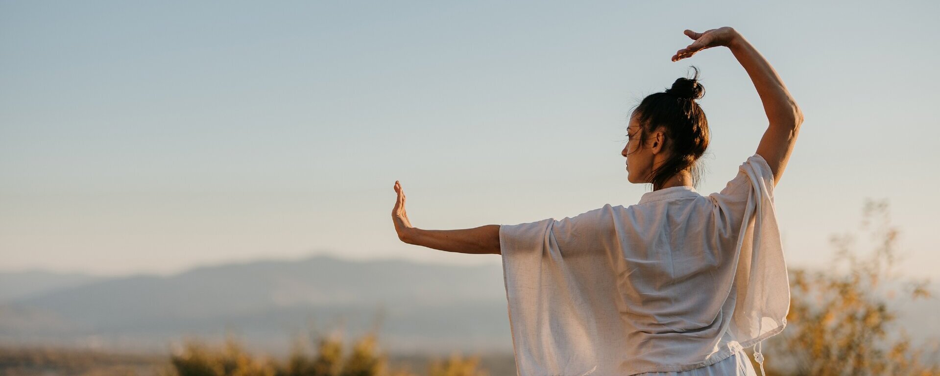 Eine Frau macht in der Natur Tai Chi.