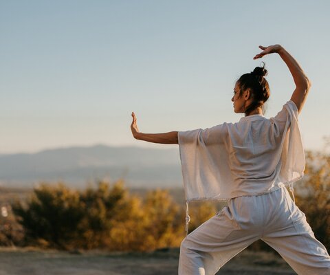 Eine Frau macht in der Natur Tai Chi.