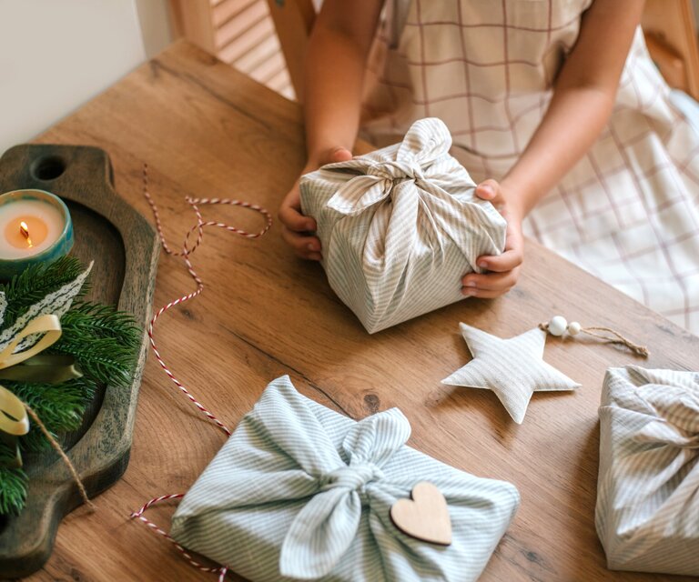 Ein Mädchen packt Geschenke nachhaltig in Stoff ein.