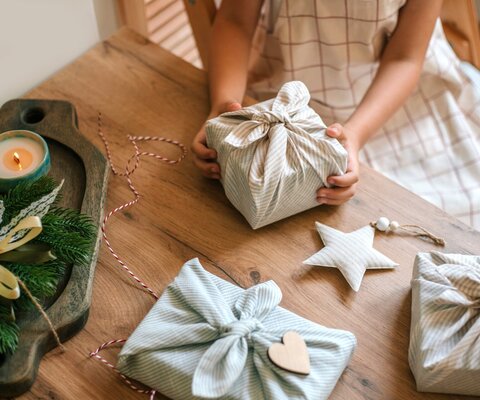 Ein Mädchen packt Geschenke nachhaltig in Stoff ein.