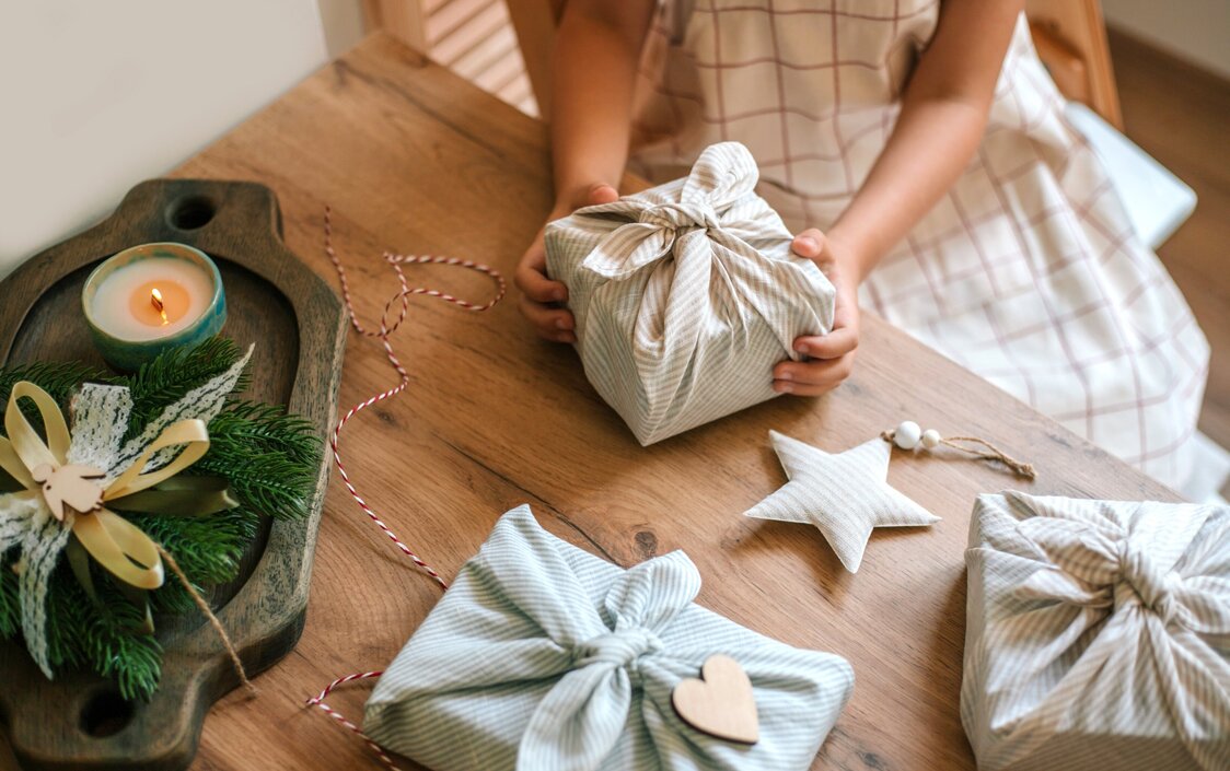 Ein Mädchen packt Geschenke nachhaltig in Stoff ein.