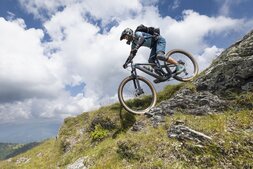 Frau mit Helm fährt auf einem Mountainbike einen Berg runter.