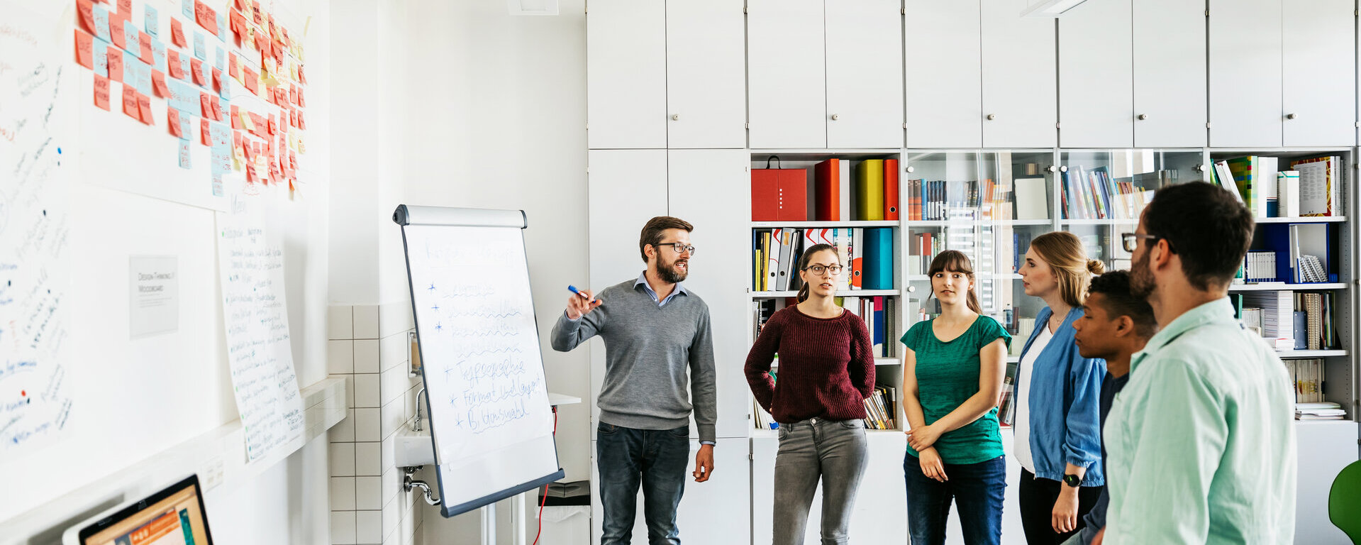 Eine Gruppe steht vor einem Flipchart.