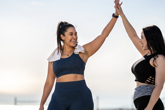 Women giving each other a high five after exercising at the beach