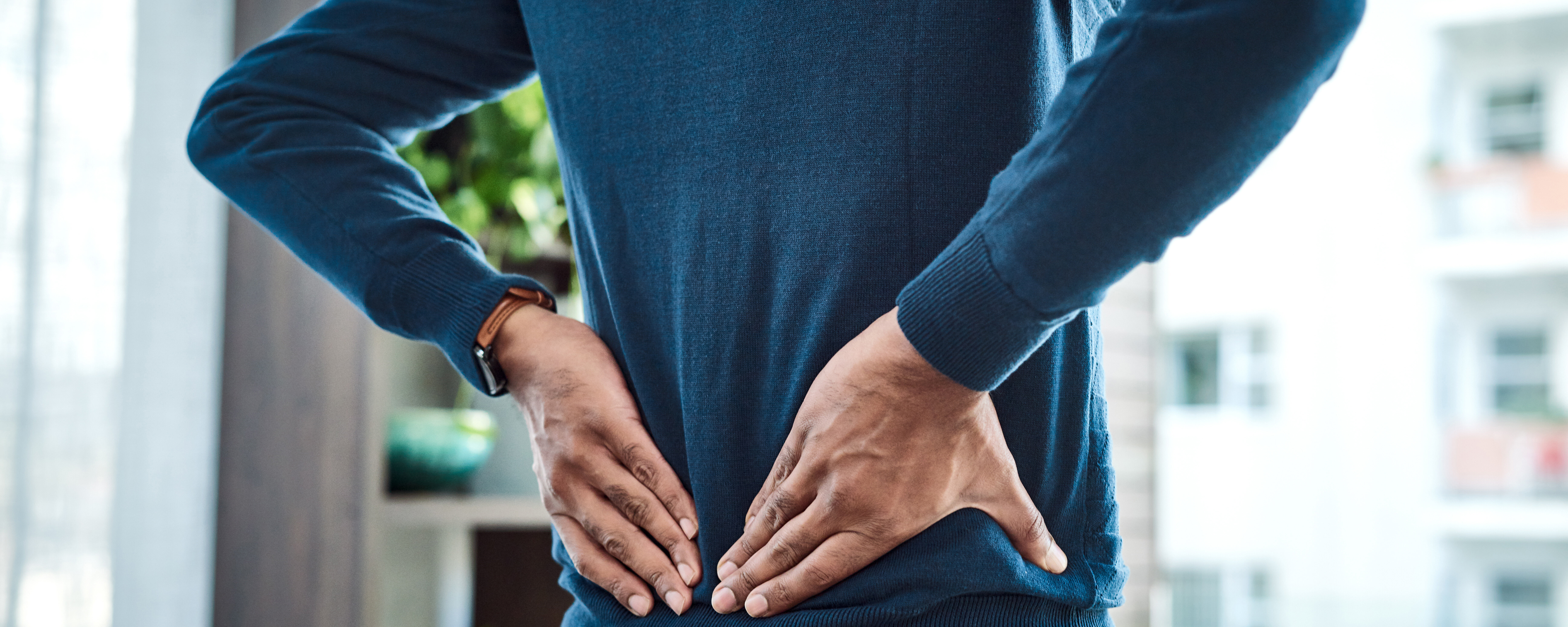 Aufnahme eines Geschäftsmannes, der während der Arbeit zu Hause unter Rückenschmerzen leidet