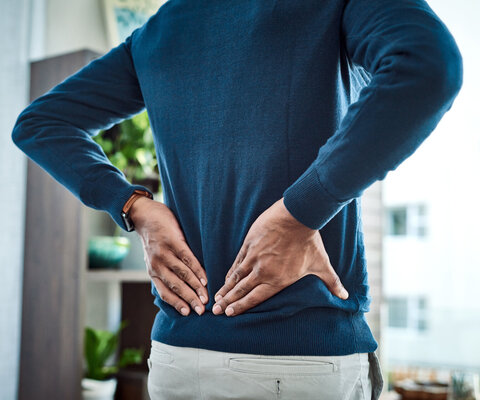 Aufnahme eines Geschäftsmannes, der während der Arbeit zu Hause unter Rückenschmerzen leidet