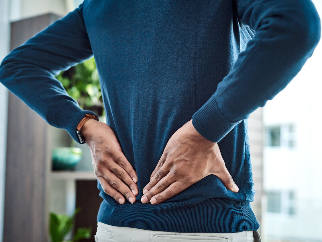 Aufnahme eines Geschäftsmannes, der während der Arbeit zu Hause unter Rückenschmerzen leidet