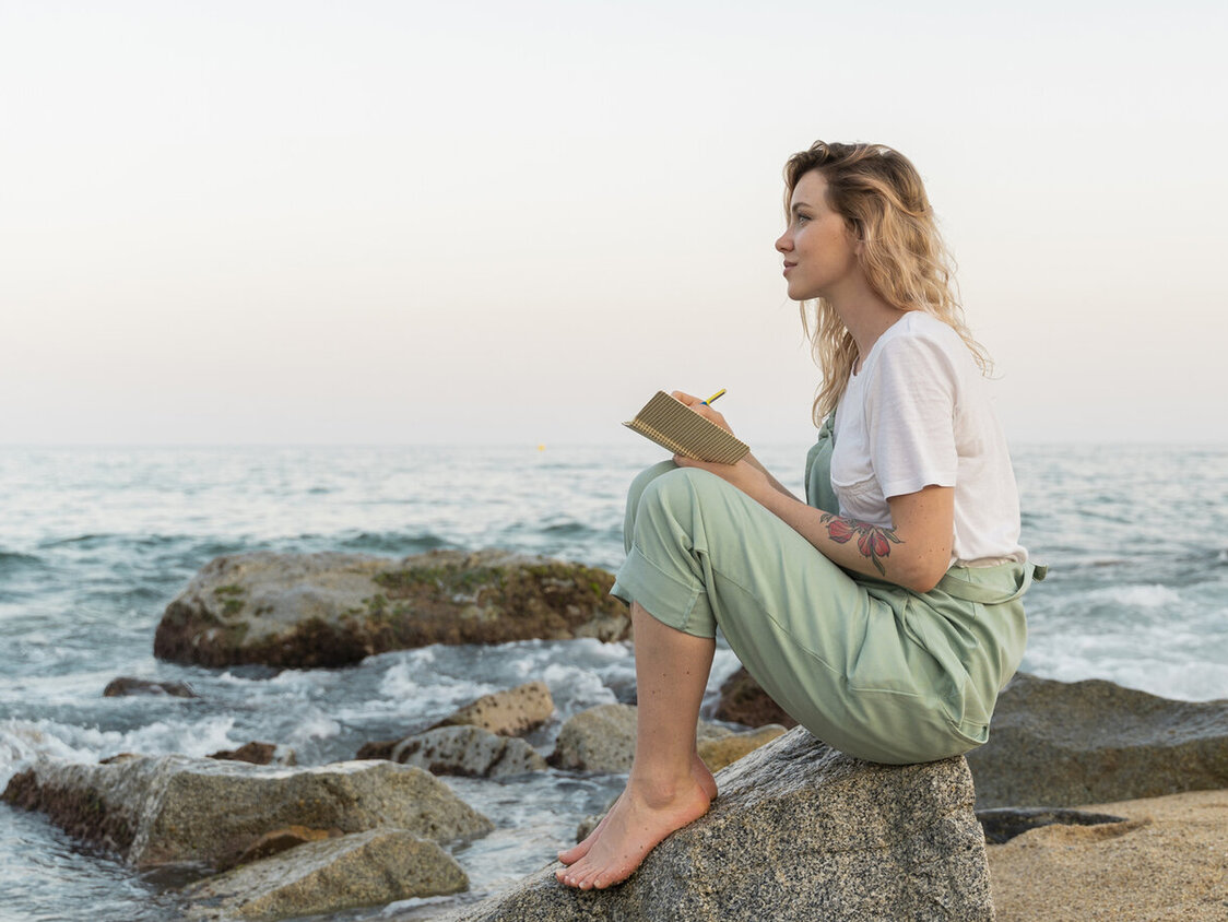 Ein junger Mann mit Bart, langen Haaren und Strohhut sitzt in einem Van, blickt über die Schulter und lächelt freundlich.