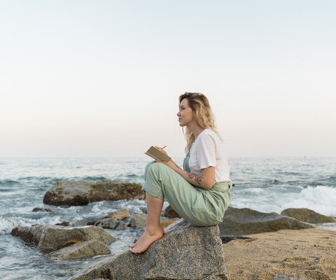 Ein junger Mann mit Bart, langen Haaren und Strohhut sitzt in einem Van, blickt über die Schulter und lächelt freundlich.