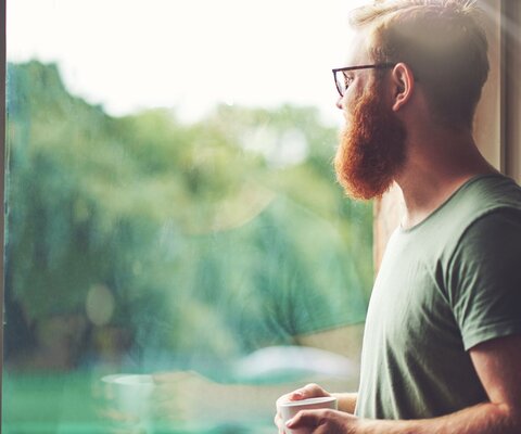 Mann schaut aus dem Fenster raus.