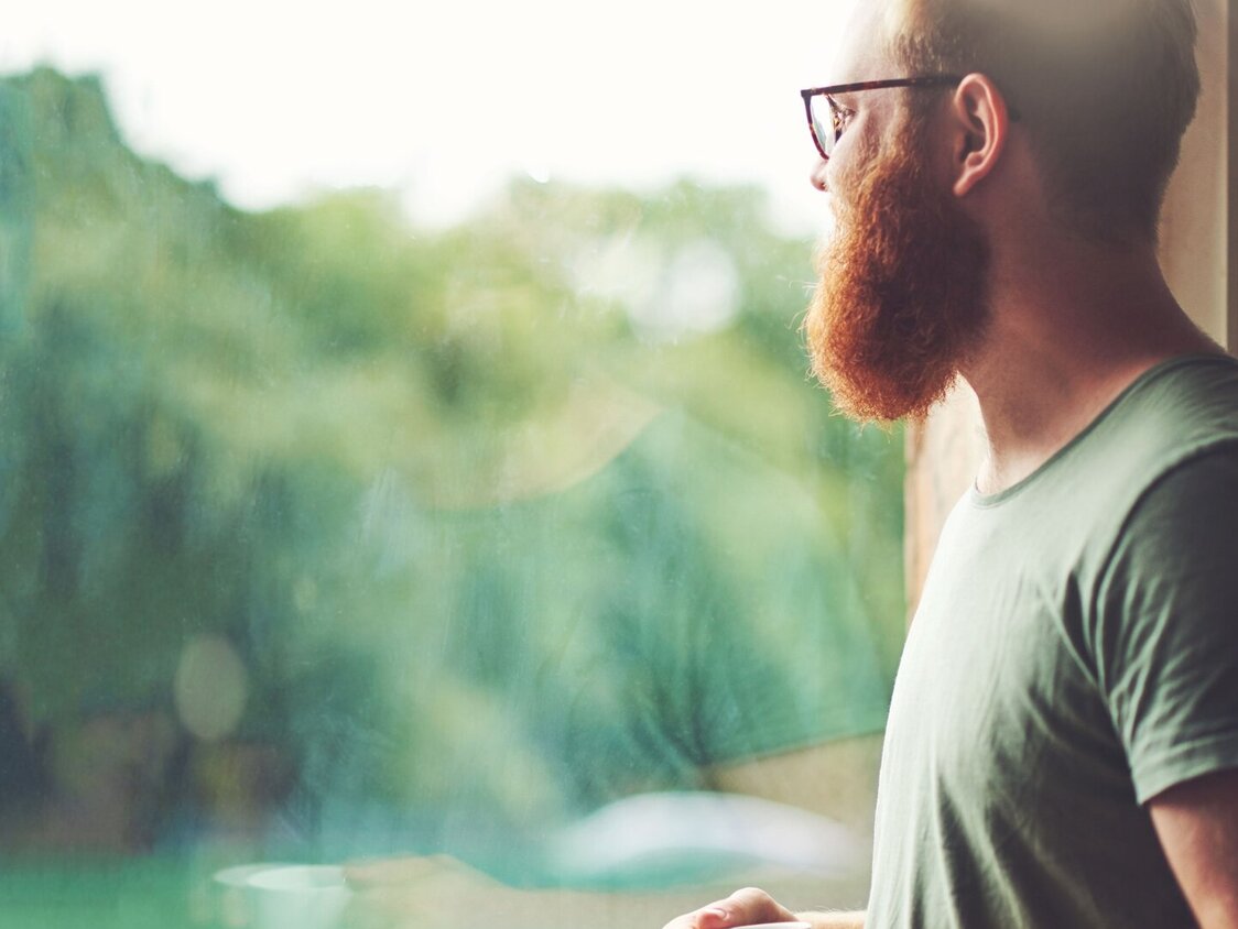 Mann schaut aus dem Fenster raus.