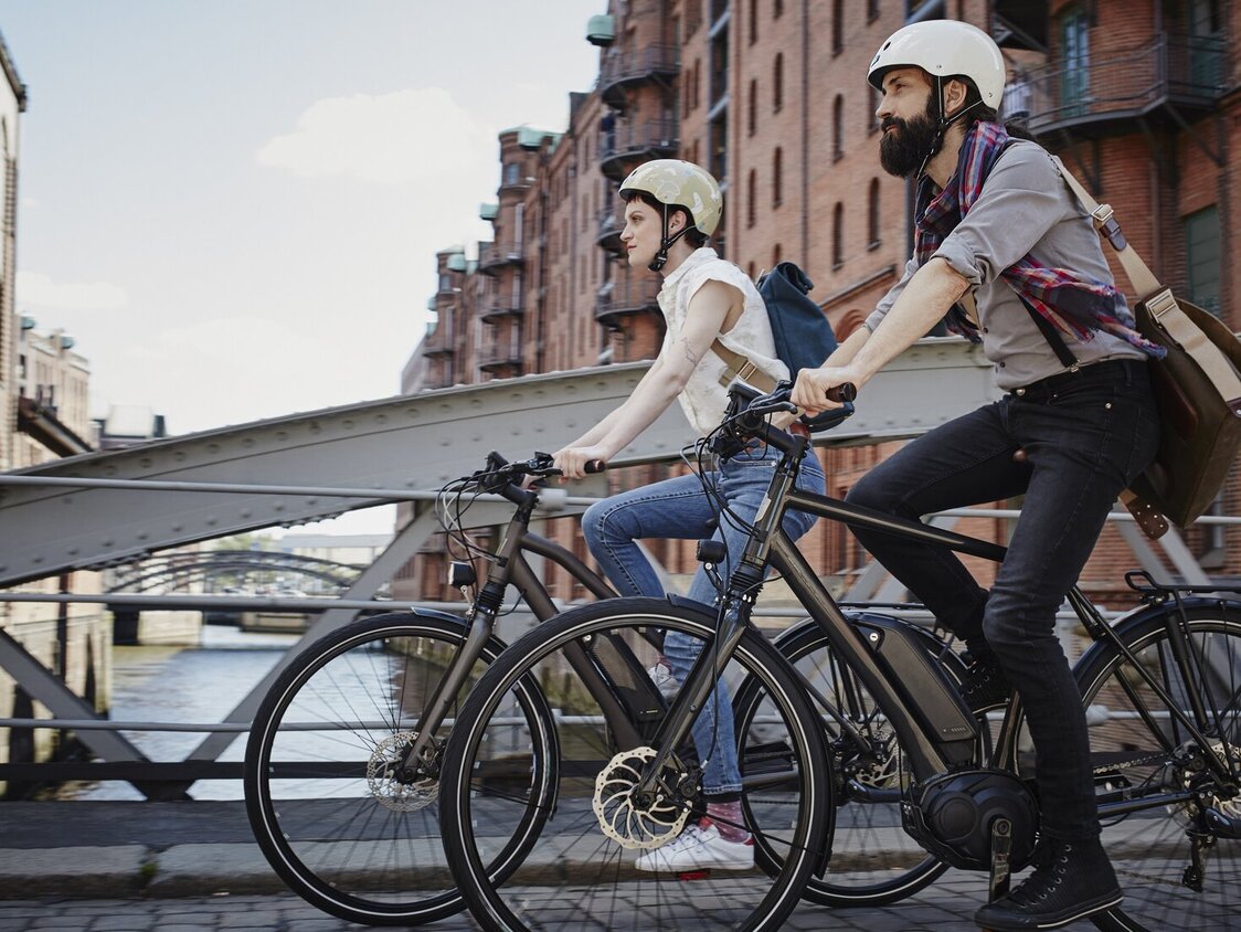Ein Paar fährt mit E-Bikes über eine Brücke in Hamburg.