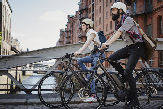 Ein Paar fährt mit E-Bikes über eine Brücke in Hamburg.