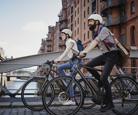 Ein Paar fährt mit E-Bikes über eine Brücke in Hamburg.